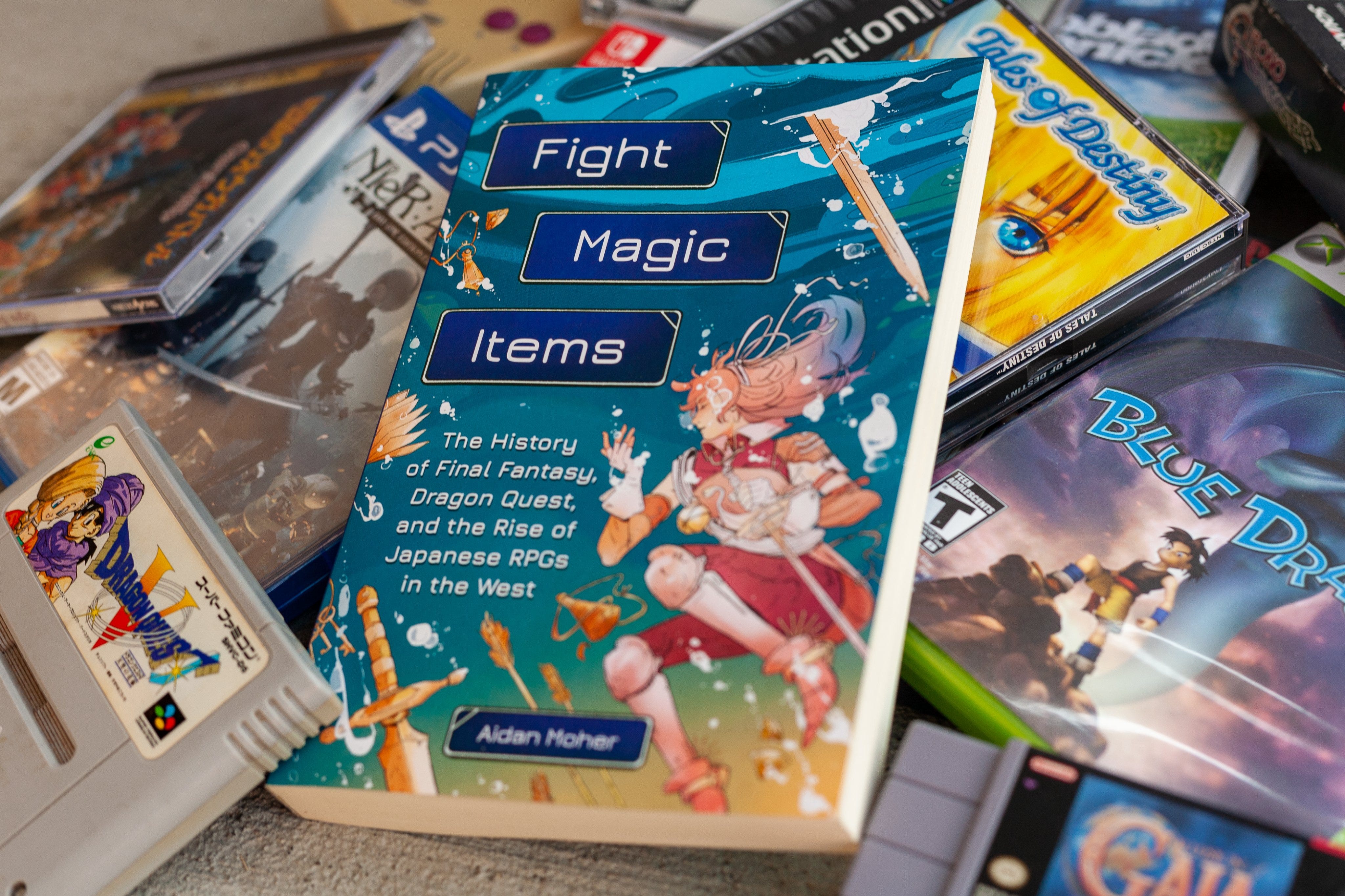 Aidan Moher's Fight, Magic, Items is featured nestled among retro video games.